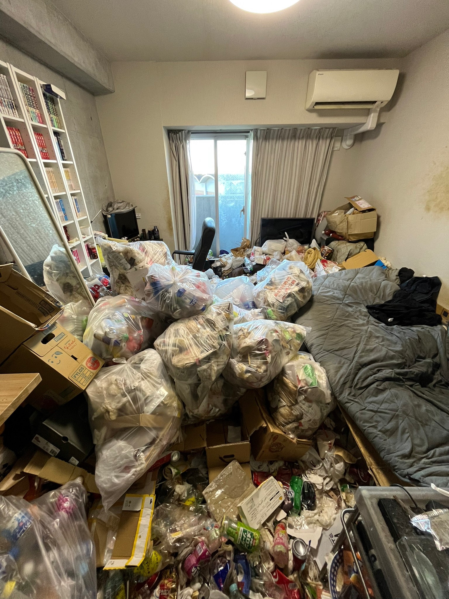 ベッド、布団、机、本棚、本、鏡、テレビ、その他生活ゴミの回収前の状態