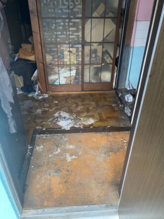 巨大なゴミ袋多数、大量の段ボール、ビン・缶類、靴、家財道具一式の回収後の状態