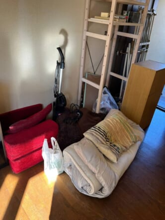 丸めた布団、座椅子、木製オープンラック、カラーボックス、掃除機などの回収前の状態