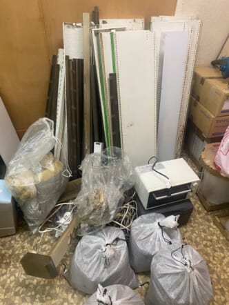 解体済みの棚板・ラック、ガラ袋(作業ゴミ)、空き段ボール、古いトースターなどの回収前の状態